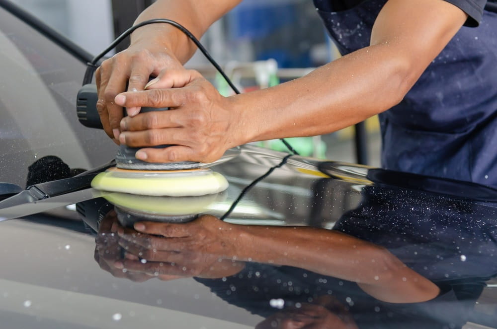 man polishing fresh auto paint on hood of car