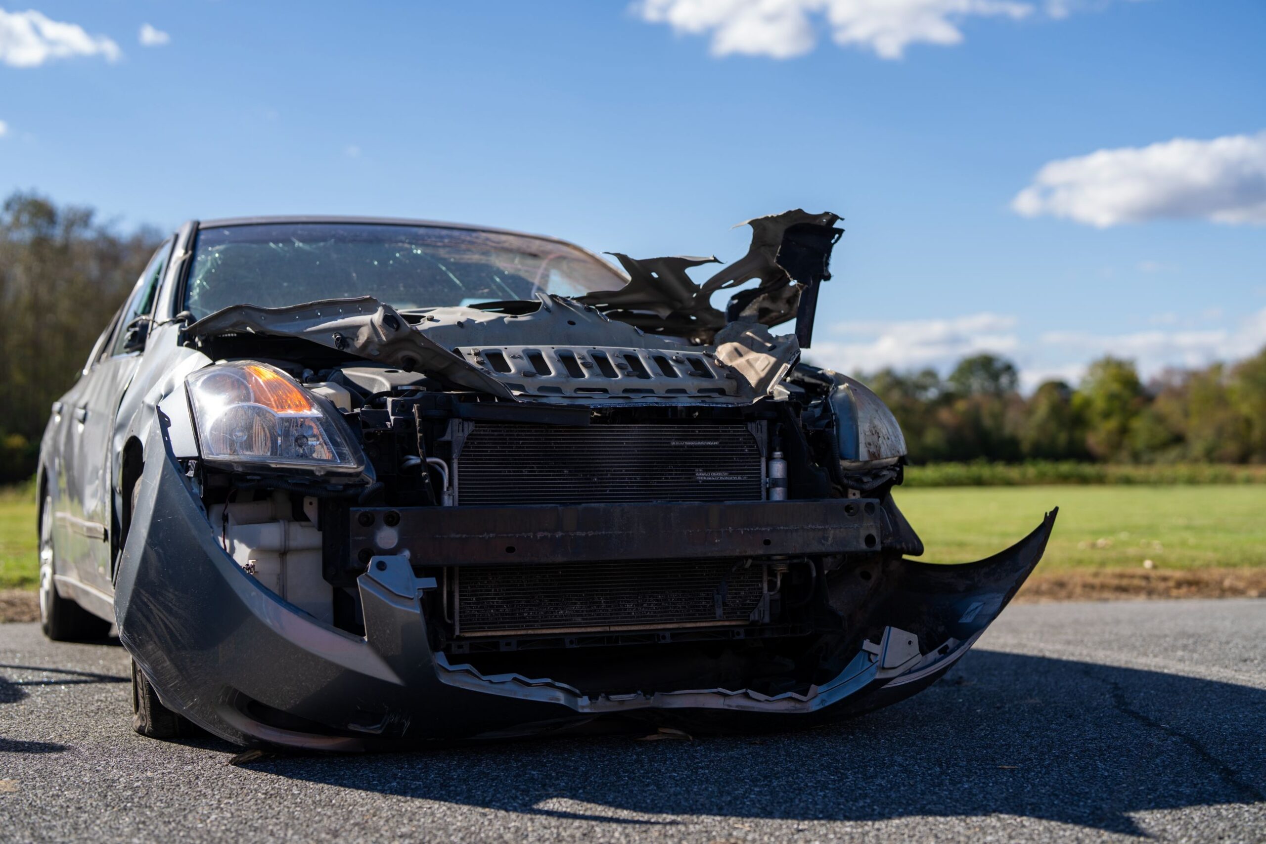 A damaged car with a severely bent front end and exposed engine components.
